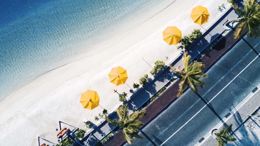 A beach with palm trees and yellow umbrellas.